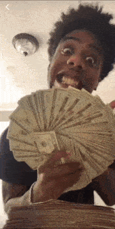 a young man is holding a stack of money in his hand .