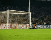a soccer goalie is diving to catch a ball in front of a playstation 2 ad