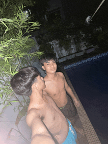 two shirtless men are standing next to each other by a pool