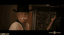 a man in a cowboy hat is smoking a cigarette in a comedy central advertisement