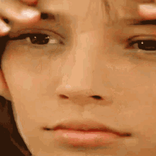 a close up of a person 's face with their hands on their face