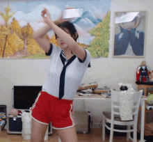 a woman wearing red shorts and a white shirt is dancing