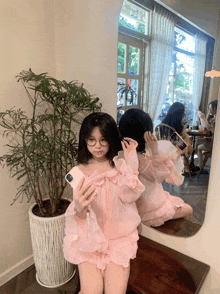 a woman in a pink dress is taking a picture of herself in front of a mirror
