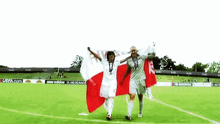 two soccer players holding a flag on a field with a uefa.com banner in the background