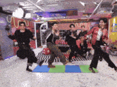 a group of young men are dancing in a room with a live music sign on the wall