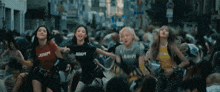 a group of girls are dancing in a crowd of people on a street .