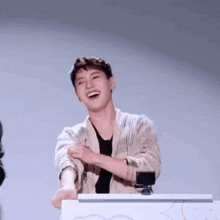 a young man is laughing while standing in front of a podium .