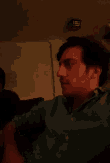 a man in a green polo shirt is sitting on a couch