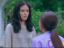 a woman in a purple shirt with the letter g on it is talking to another woman