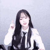 a girl with long black hair wearing a white shirt and tie is pointing up