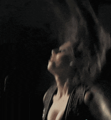 a woman in a black dress is dancing in a dark room with her breast exposed .