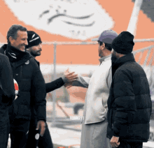 a man in a purple hat shakes hands with two other men