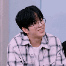 a young boy wearing glasses and a plaid shirt smiles