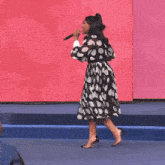 a woman in a black and white polka dot dress is singing into a microphone