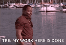 a man is standing in front of a body of water with boats in the background and says `` my work here is done '' .