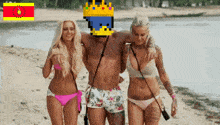 a man with a crown on his head is walking with two women on the beach