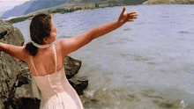 a woman in a white dress is standing in the water with her arms outstretched and ayngaran written on the bottom