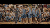 a group of men are standing in a line with a man standing in the middle