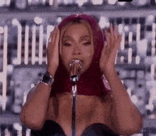 beyonce is wearing a red scarf around her head and singing into a microphone .