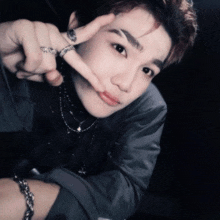 a young man with a bracelet on his wrist is making a peace sign