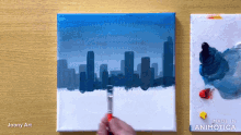 a painting of a city skyline is being painted on a canvas by joony art