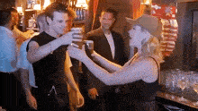 a woman in a cowboy hat is toasting a man with a beer