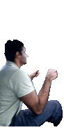 a man in a white shirt sits on the floor with his hands folded