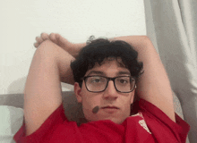 a man wearing glasses and a red shirt with the word liverpool on the sleeve