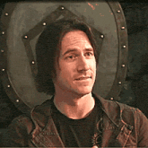 a man in a black shirt and a brown jacket is smiling