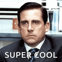 a man in a suit and tie is sitting in an office and making a face .