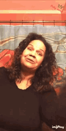 a woman with curly hair is making a funny face in front of a shower curtain ..