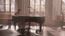 a man is sitting at a piano in a room with a lamp
