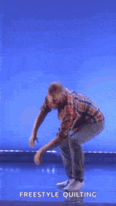 a man in a plaid shirt is standing on a stage with a blue background .