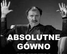 a black and white photo of a man with his hands up and the words absolutne gowno below him