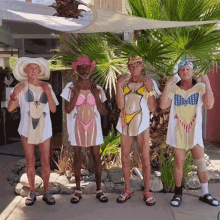 a group of men wearing bikinis and cowboy hats pose for a picture