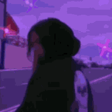 a woman wearing a mask is standing in front of a purple background .