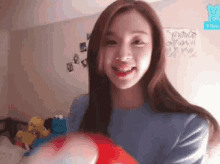 a woman in a blue sweater is holding a red balloon in her hands .