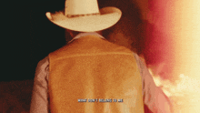 a man in a cowboy hat and vest stands in front of a fire with the words " what don 't belong to me "