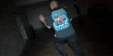 a man in a black t-shirt is dancing in a dark room .