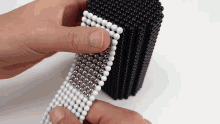 a person is playing with a stack of black and white beads