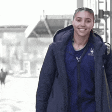 a woman wearing a blue jacket that says ucla on it