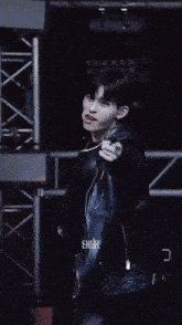 a young man wearing a black leather jacket is dancing on stage