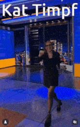 a woman dancing in front of a sign that says kat timpf