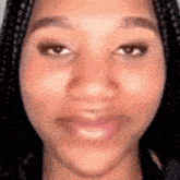 a close up of a woman 's face with braids on her hair .