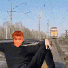 a man in a black shirt is sitting on a train track