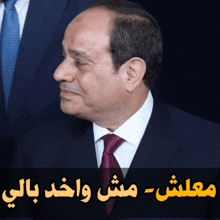 a man in a suit and tie with arabic writing on the bottom right