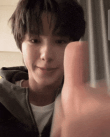a close up of a person 's face with a hand pointing at the camera