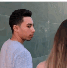 a man in a grey shirt is looking at a woman in a white tank top