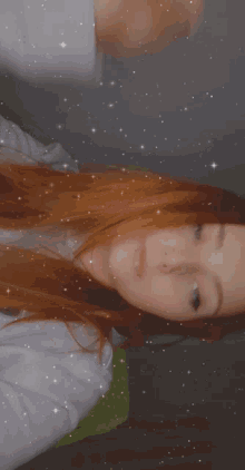 a woman with red hair and blue eyes is laying down and looking at the camera