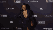 a woman stands on a red carpet with jbl and clive davis on it